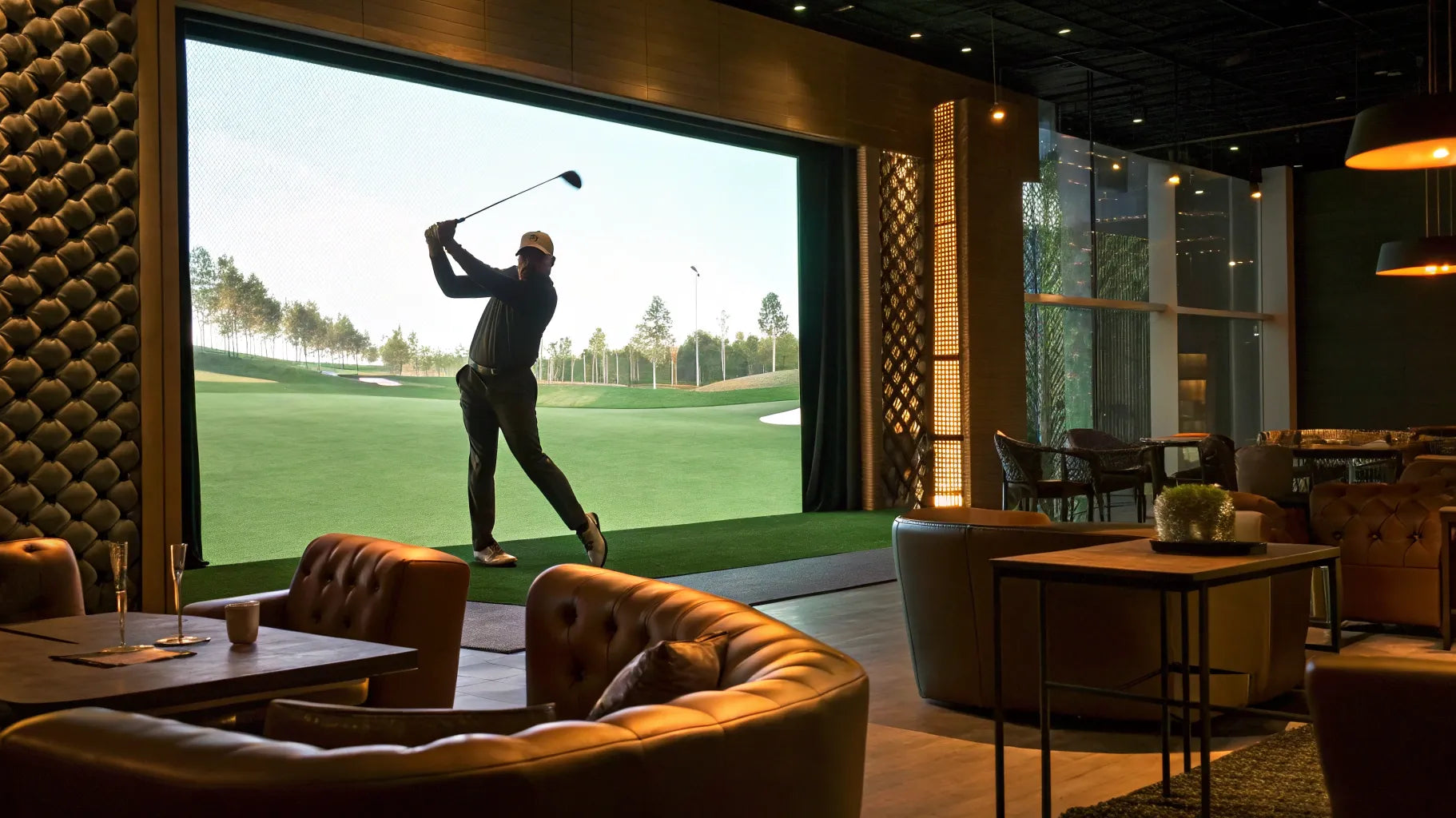 A golfer swings at an indoor golf simulator in a modern sports bar.