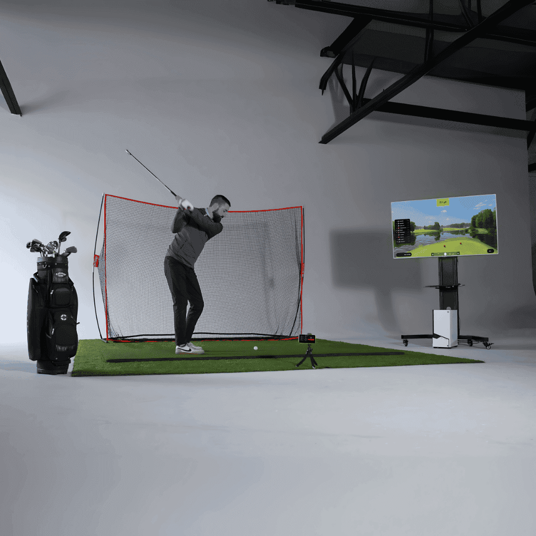 Person practicing golf swings in a simulator setup with a screen displaying a golf course.